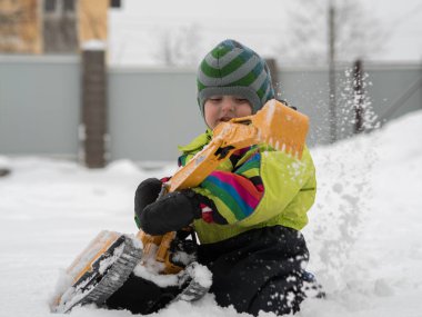 Tarak beyaz karda oynarken kış tulum giymiş şirin çocuk