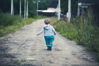 Sevimli kıvırcık bebek botları ve kauçuk pantolon çalışan bir ülke yol boyunca giymiş. Yaz aylarında eğlenceli kırsal kesimde.