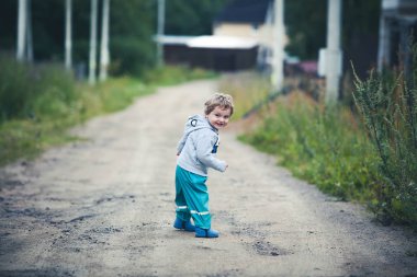 Sevimli kıvırcık bebek botları ve kauçuk pantolon çalışan bir ülke yol boyunca giymiş. Yaz aylarında eğlenceli kırsal kesimde.