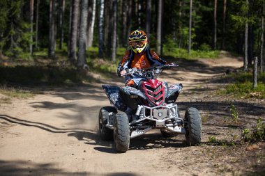 Saint-Petersburg, Rusya-Temmuz 2014: ormanda bir Atv Yamaha Raptor R700 bilinmeyen kişini. O binmek tekerlekleri altında kum ve toz sinek içinde. Bir takım elbise ve kask Fox kafa giymiş.