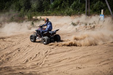 Saint-Petersburg, Rusya-Temmuz 2014: ormanda bir Atv Yamaha Raptor R700 bilinmeyen kişini. O binmek tekerlekleri altında kum ve toz sinek içinde. Bir takım elbise ve kask Fox kafa giymiş.