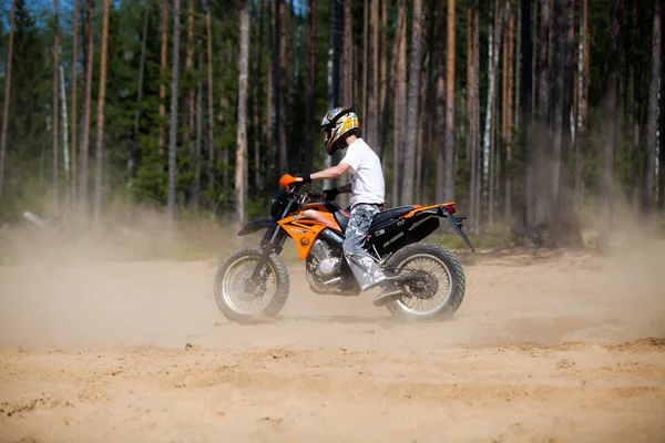 SAINT-PETERSBURG, RUSIA - JULIO 2014: Niño desconocido que monta en el bosque en una motocicleta Yamaha xt125x. Motociclistas cabalgan en la arena y el polvo vuela bajo las ruedas . — Foto de Stock