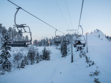 Ruka, Finlandiya - Ocak 2017: dağ ve yolları üzerinde gökyüzü snowboards gidip gelirken koltuklu teleferik. Kayak Merkezi, kar, aşırı tatil, aktif tatiller.