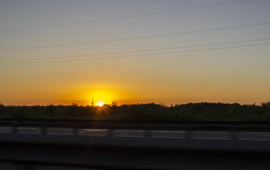 Orman otoyolu yakınında, üzerinde turuncu günbatımı