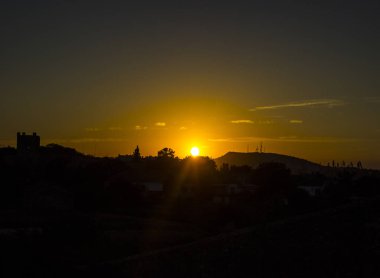 Dağlık arazide güzel bir günbatımı küçük bir yerleşim yeri ve güneşin altın ışınlarını görebilirsiniz.
