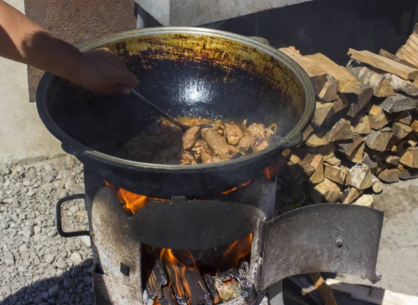 Panela de ferro fundido para a cozinha tradicional da Rússia, fica ao lado da madeira. ver o fogo — Fotografia de Stock