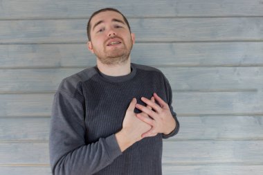 Gri kazaklı bir adam kalbi incitir. Virüs hastalığı vakası.