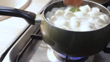 Etli börekler mutfakta kaynar suda pişirilir. Aşçı çorbayı bir yemek makinesiyle karıştırıyor, iştahı açıyor.