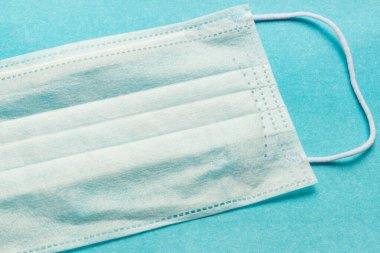 İnsanları tehlikeli bir virüsten korumak için mavi bir tıbbi tek kullanımlık maske 2020 renk eğiliminin arka planında yatıyor. Çin 'de koronavirüs salgını için sağlık ve tıbbi konsept. Termometre yüksek sıcaklık gösteriyor