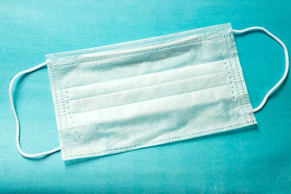 İnsanları tehlikeli bir virüsten korumak için mavi bir tıbbi tek kullanımlık maske 2020 renk eğiliminin arka planında yatıyor. Çin 'de koronavirüs salgını için sağlık ve tıbbi konsept. Termometre yüksek sıcaklık gösteriyor