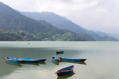 Açık bir gölün yüzeyinde, farklı renklerde küçük tekneler. Turistik tatil beldesinde turist bulunmuyor. Sınırlar koronavirüs nedeniyle kapalı ve ticarete zarar veren turist sayısı azalıyor.