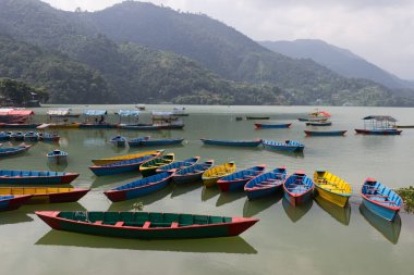 Açık bir gölün yüzeyinde, farklı renklerde küçük tekneler. Turistik tatil beldesinde turist bulunmuyor. Sınırlar koronavirüs nedeniyle kapalı ve ticarete zarar veren turist sayısı azalıyor.