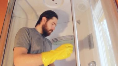 Koronavirüs sırasında ev güvenliği için duş kabinini temizliyor. Gri tişörtlü ve sakallı bir adam, banyoyu dezenfekte ediyor. Sağlığa iyi gelen güçlü bir bağışıklık sistemi.