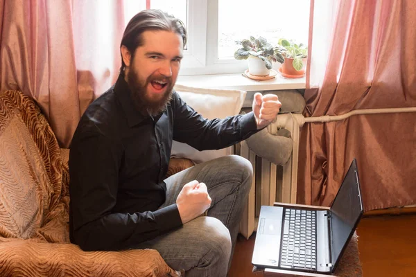 self-isolation mode in the world due to the coronavirus problem.a man with dark hair and a thick beard, works at home as a self-employed remote worker.laptop and phone, bad emotions of anger and fear