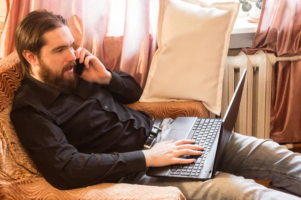 self-isolation mode in the world due to the coronavirus problem.a man with dark hair and a thick beard, works at home as a self-employed remote worker.laptop and phone, bad emotions of anger and fear