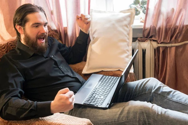 self-isolation mode in the world due to the coronavirus problem.a man with dark hair and a thick beard, works at home as a self-employed remote worker.laptop and phone, bad emotions of anger and fear