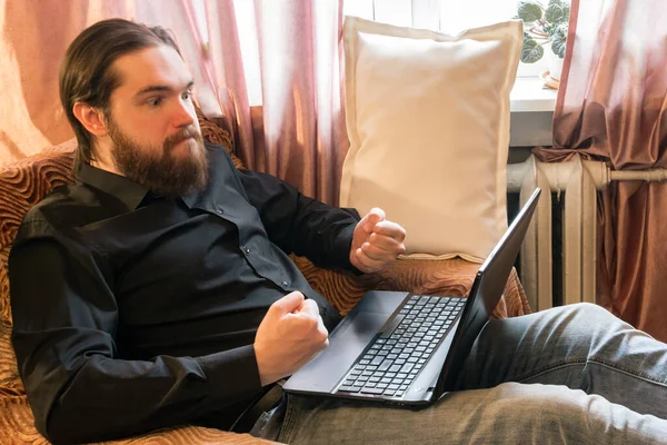 self-isolation mode in the world due to the coronavirus problem.a man with dark hair and a thick beard, works at home as a self-employed remote worker.laptop and phone, bad emotions of anger and fear