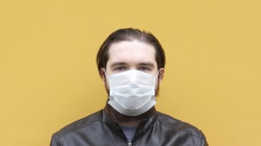 Tek kullanımlık maskeli yetişkin bir adam hapşırır. Solunum cihazının düzgün bir şekilde nasıl takılacağı ve maske takılacağı konusunda talimatlar. Koronavirüs sırasında sevdiklerinizi izolasyon ve önlemlerle korumak..