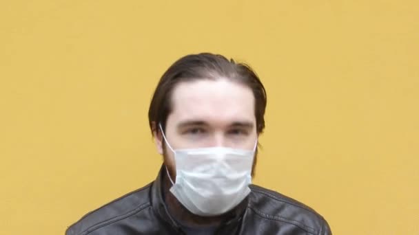 使い捨てマスクの大人の男がくしゃみをする 呼吸器やマスクを正しく着用する方法については コロナウイルス中の自己分離と予防策で愛する人を保護してください — ストック動画