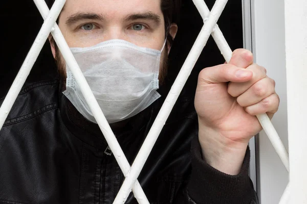 Tek kullanımlık maskeli, siyah saçlı, sakallı ve deri ceketli bir erkek manken. Coronavirus hastası evde karantina ve hastalık önleme altında kalmasına karşın, ev hapsinden kaçmak istiyor..