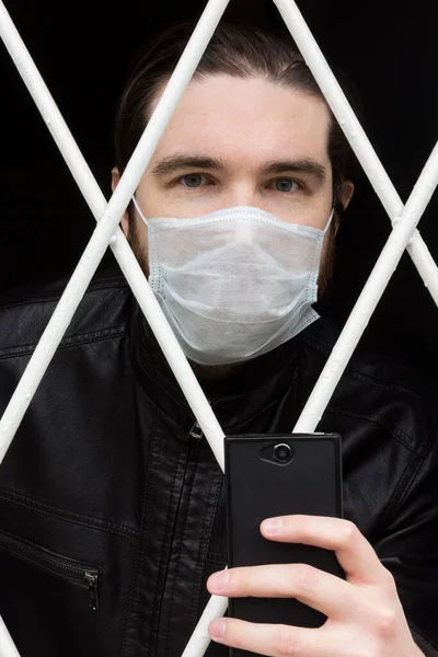 Tek kullanımlık maskeli, siyah saçlı, sakallı ve deri ceketli bir erkek manken. Coronavirus hastası evde karantina ve hastalık önleme altında kalmasına karşın, ev hapsinden kaçmak istiyor..