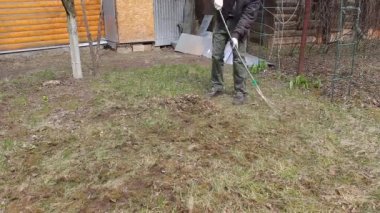 Koronavirüsten korunmak için tek kullanımlık maske takan genç adam, ağaç yapraklarından bahar temizliği yapıyor. Rüzgar saçlarını değiştiriyor. Doğa koruma kavramı ve çöpten orman temizliği kavramı.