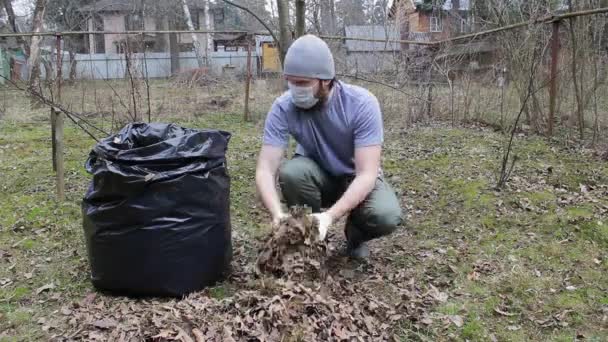 Чоловік Хіпстерському Стилі Одноразовій Масці Робить Весняне Прибирання Саду Листя — стокове відео