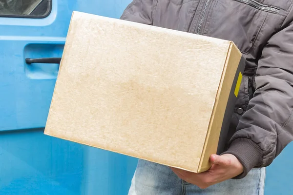 logistics worker delivery parcel, food delivery service by car under quarantine, disease outbreak, coronavirus pandemic conditions. close-up of cardboard box holding by a male courier without gloves