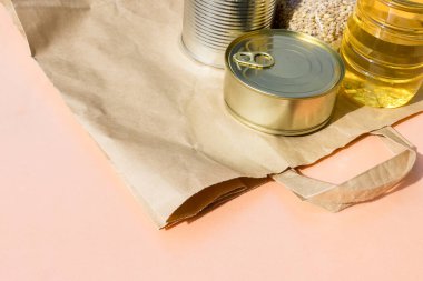 Pembe arka planda yürüyüş yapmak için poşet dolusu yiyecek. Coronavirus karantinası sırasında yiyecek teslimatı: konserve yiyecek, tahıl gevreği, yağ. Uzun depolama yiyecek ve ürünler öncelikli gereklilik yakın çekim