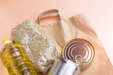 Pembe arka planda yürüyüş yapmak için poşet dolusu yiyecek. Coronavirus karantinası sırasında yiyecek teslimatı: konserve yiyecek, tahıl gevreği, yağ. Uzun depolama yiyecek ve ürünler öncelikli gereklilik yakın çekim