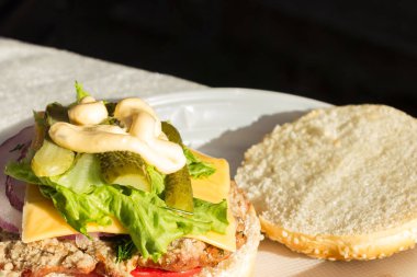 Salatalık, domates, marul, iştah açıcı sos ve soğanlı lezzetli ev yapımı hamburger. Lezzetli fast food konsepti. Kopyalama alanı