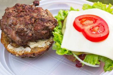 Et, yeşil salata, soğan, baharatlı sos ve domatesten yapılmış lezzetli bir burger lezzetli görünüyor. Tatillerde kendin pişir.