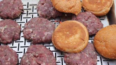 Hamburgerler ve et pirzolaları ızgarada kızartılmak üzere hazırlanır. Kendini soyutlama sırasında ev yapımı yemekler.