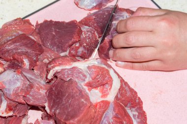 Bir adam çiğ eti bıçakla keser. Satılık kıyma hazırlığı ve üretimi