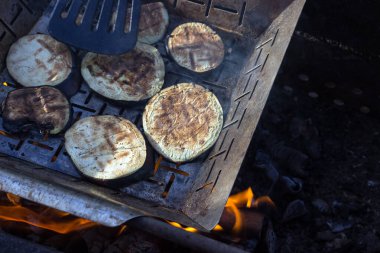 Izgarada dilimlenmiş ve kızartılmış patlıcanlar. Aşçı sebzeleri dönüştürmek için bir spatula kullanır. Karantina bittikten sonra vejetaryen mutfağı ve sağlıklı yiyecekler