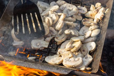 Sulu iştah açıcı şampiyonlar ızgarada ya da barbekü buharında pişiriliyor. Aşçı mantarları bir mutfak spatulasıyla karıştırır. Seçici odaklanma. Yemek arkaplanı. Vejetaryenler için lezzetli sağlıklı yemekler..