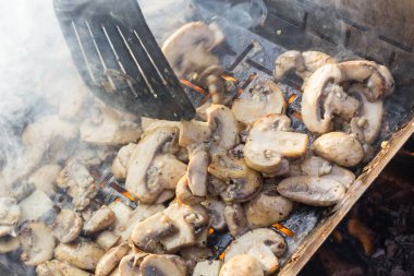 Sulu iştah açıcı şampiyonlar ızgarada ya da barbekü buharında pişiriliyor. Aşçı mantarları bir mutfak spatulasıyla karıştırır. Seçici odaklanma. Yemek arkaplanı. Vejetaryenler için lezzetli sağlıklı yemekler..