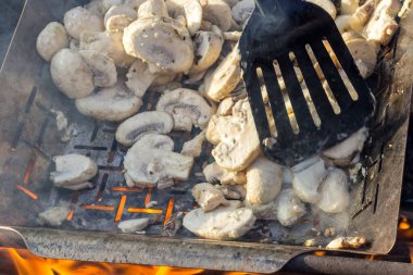 Sulu iştah açıcı şampiyonlar ızgarada ya da barbekü buharında pişiriliyor. Aşçı mantarları bir mutfak spatulasıyla karıştırır. Seçici odaklanma. Yemek arkaplanı. Vejetaryenler için lezzetli sağlıklı yemekler..