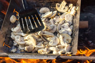 Sulu iştah açıcı şampiyonlar ızgarada ya da barbekü buharında pişiriliyor. Aşçı mantarları bir mutfak spatulasıyla karıştırır. Seçici odaklanma. Yemek arkaplanı. Vejetaryenler için lezzetli sağlıklı yemekler..