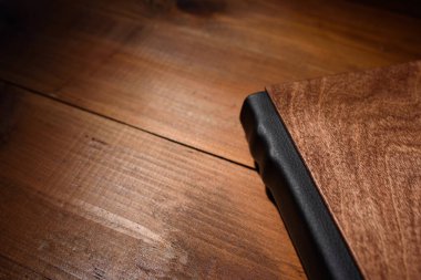 Photo book in a wooden cover on a wooden table. Hard light
