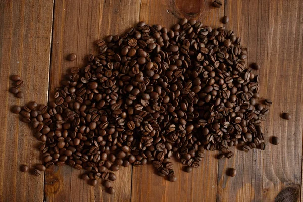 Кофе зерно посыпать на деревянный стол с текстурой — стоковое фото