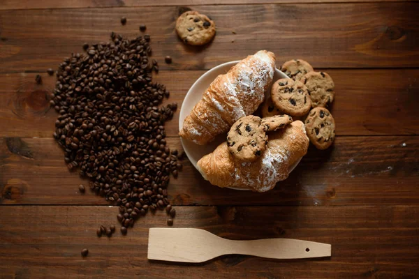 朝食のカプチーノ、クロワッサン、木製のテーブルに美味しいクッキー. — ストック写真