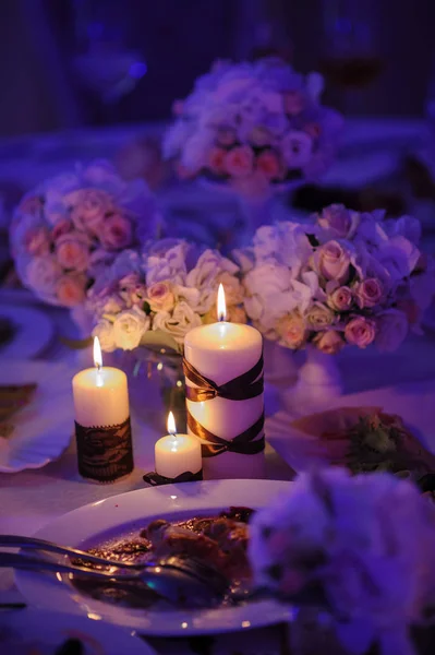 Bonita, mesa decorada com decorações de flores e velas vermelhas. Noite de Natal ou decoração de festa de casamento . — Fotografia de Stock