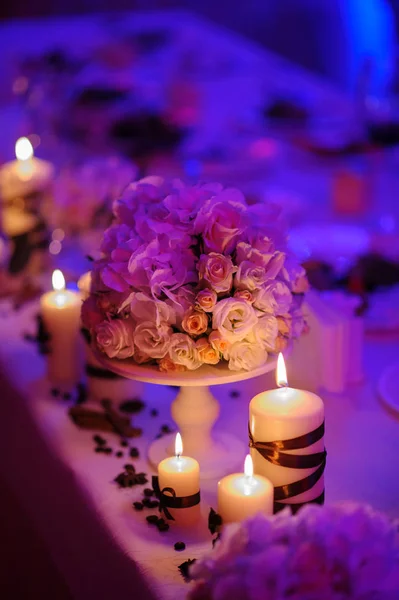 Bonita, mesa decorada com decorações de flores e velas vermelhas. Noite de Natal ou decoração de festa de casamento . — Fotografia de Stock