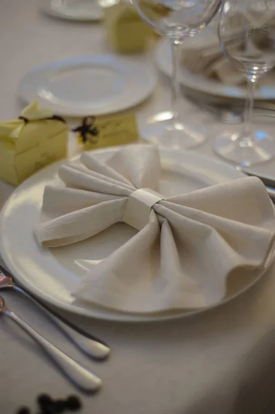 Mesa decorada lindamente elegante para férias - dia de casamento ou dia dos namorados com talheres modernos, arco, vidro, vela e presente, close-up, tonificado — Fotografia de Stock