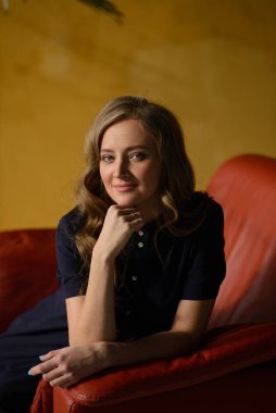 Güzel genç bir kadın bir koltukta oturuyor.