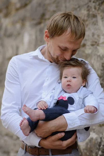 Genç babanın portresi beyaz tuğla duvarda ağlayan bir kız çocuğu tutuyor.