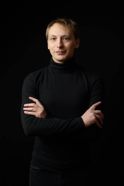 Siyah giyinmiş, siyah arkaplan giyen kararlı yakışıklı bir adamın portresi..