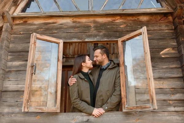 couple in love looks out of the window, wooden house. The concept of buying new housing for young families.