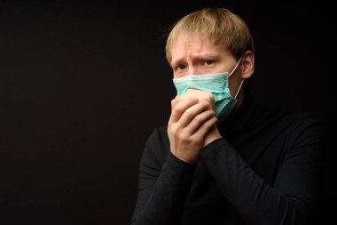 Tıbbi yüz maskesi olan orta yaşlı bir adam yakın plan karanlık arka planda pandemik koronavirüs hastalığını gösteriyor. Covid-19 salgın kirliliği kavramı.